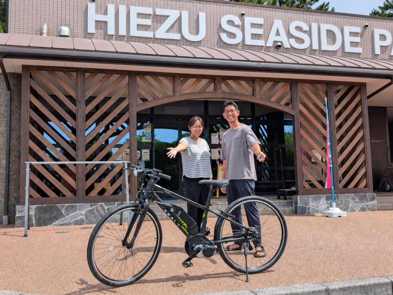 日吉津村海浜運動公園の建物前で、電動アシスト自転車を紹介する二人の管理者
